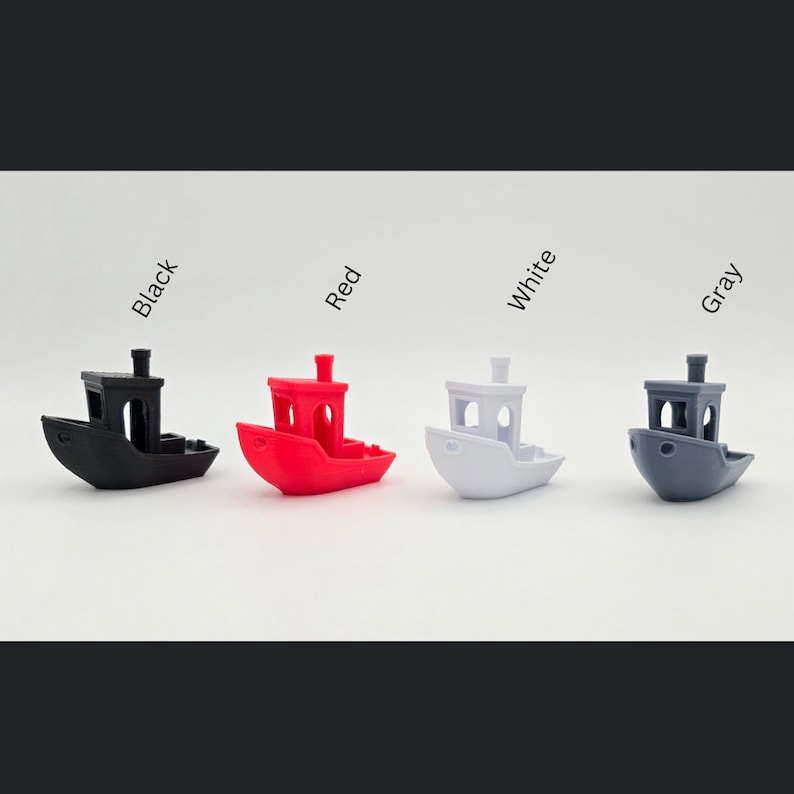 May include: Four miniature toy tugboats in black, red, white, and gray. The boats are all the same design with a small cabin and a smokestack.