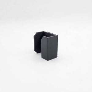 May include: A matte black, U-shaped desk organizer. The organizer has a rectangular base and two upright sections, creating a space for holding items. The design is simple and modern, suitable for office or home use.