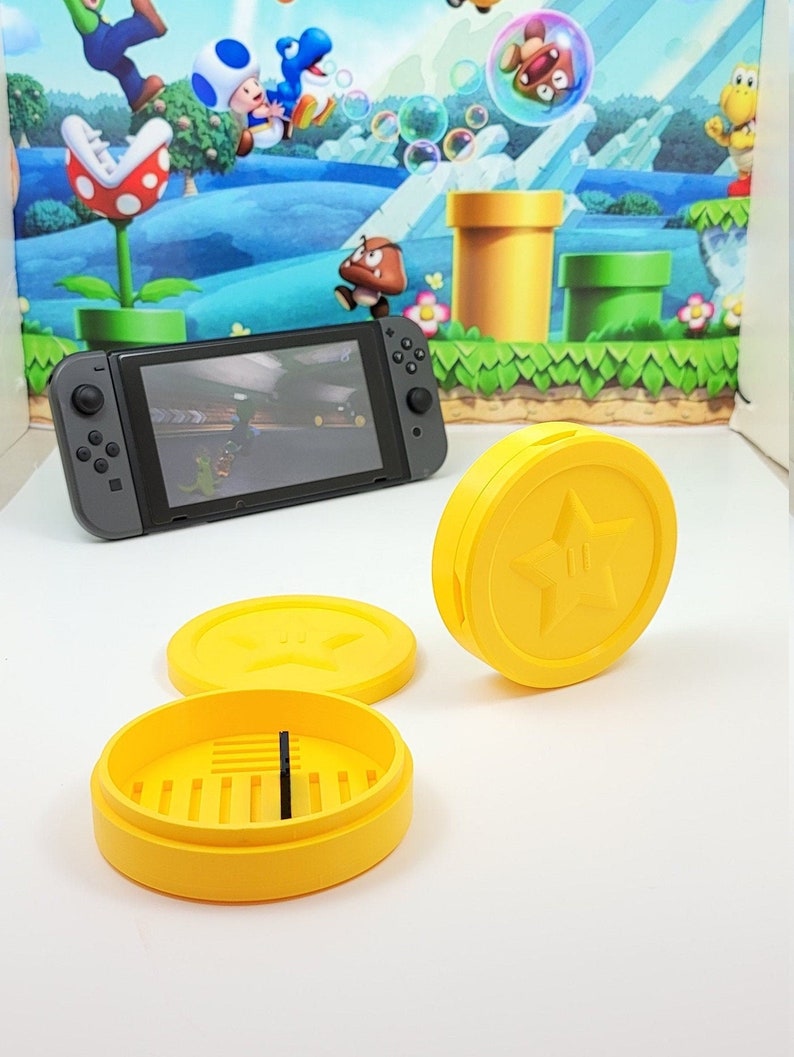 May include: Three yellow plastic containers with a star design. The containers are for storing small items, such as video game cartridges. The containers are on a white surface.