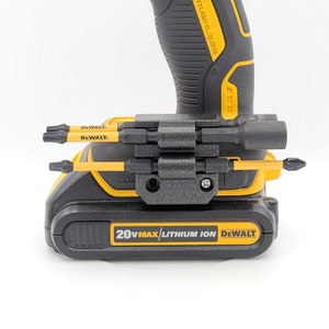 May include: A black and yellow DeWalt 20V Max Lithium Ion drill with a black bit holder attached to the side. The bit holder has several different bits inserted into it.