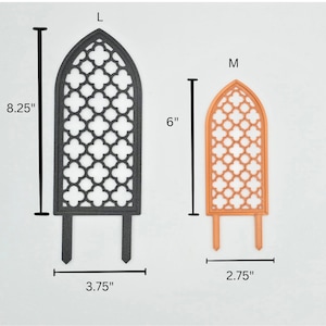 May include: Two decorative metal garden trellises, one black and one orange. The larger trellis is 8.25 inches tall and 3.75 inches wide. The smaller trellis is 6 inches tall and 2.75 inches wide. Both trellises have a gothic arch design with a lattice pattern.