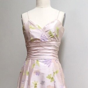 May include: A pink sleeveless dress with a floral print. The dress has a V-neckline and a fitted bodice. The skirt is full and flowing.