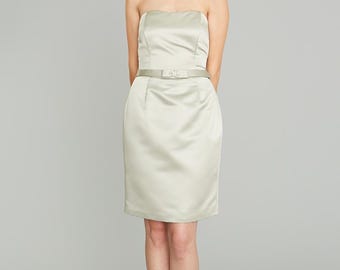 May include: A strapless, light-coloured satin dress with a fitted bodice and a skirt that falls to the knees. The dress has a matching satin belt with a buckle.