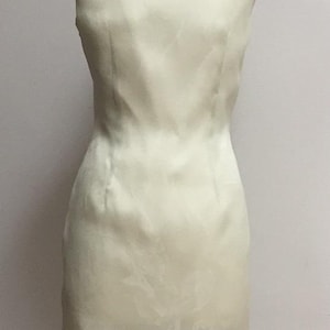 Puede incluir: Un vestido sin mangas de color verde claro con un patr&oacute;n sutil. El vestido es entallado y tiene una falda recta.