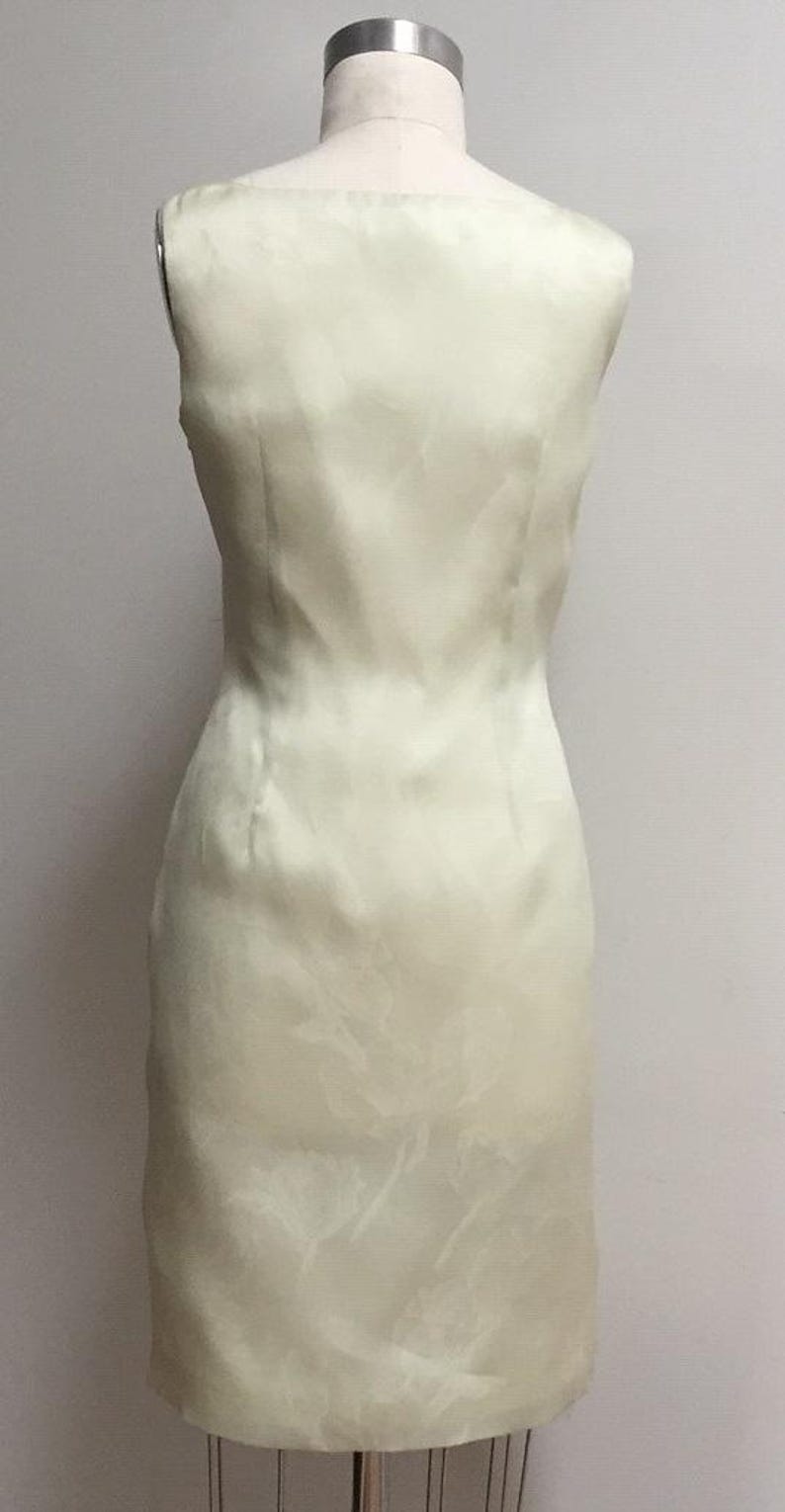 Puede incluir: Un vestido sin mangas de color verde claro con un patr&oacute;n sutil. El vestido es entallado y tiene una falda recta.