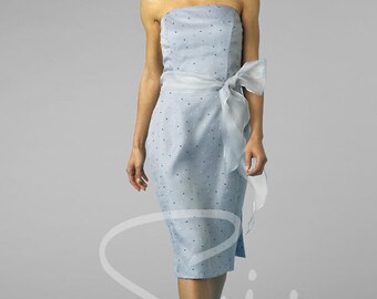 May include: A pale blue, knee-length strapless dress with a white sash tied in a bow. The dress is embellished with small, scattered details. The model is wearing white strappy heels. The dress is approximately 100 cm in length.