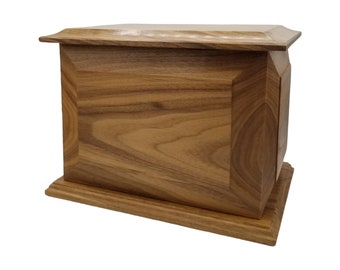 May include: A wooden cremation urn with a light brown finish and a simple, rectangular design.