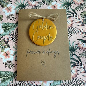 May include: A brown card with a gold circle ornament that says "Golden Couple" and the text "forever & always" with a heart symbol.