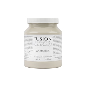 May include: A 16.9 fluid ounce bottle of Fusion Mineral Paint in the color Champlain. The bottle is white with a black label and the text "Fusion Mineral Paint Paint it beautiful. Champlain Foundation to Finish All In One 500mL 16.9 fl oz"