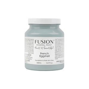 May include: A 16.9 fluid ounce bottle of Fusion Mineral Paint in the color French Eggshell. The bottle is light blue and has a white label with the Fusion logo and the words "Paint it beautiful".