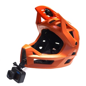 May include: An orange full-face bicycle helmet with a black GoPro camera mounted on the side.