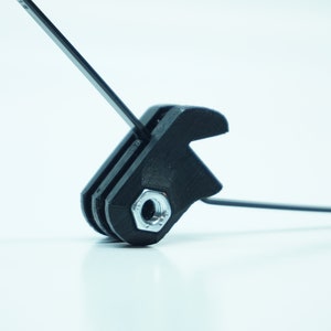 May include: A black plastic camera mount with a silver screw. The mount has a threaded hole for attaching a camera or other accessory.