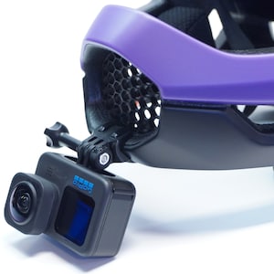 May include: A black GoPro camera mounted on a purple helmet with a black mount.
