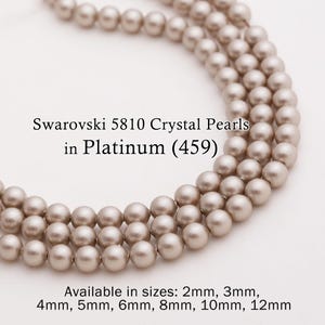 May include: Close-up of three strands of Swarovski 5810 Crystal Pearls in Platinum (459). The pearls are a light, silvery-gray color and are available in sizes from 2mm to 12mm.