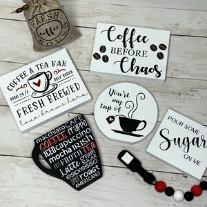 May include: A collection of coffee-themed wooden signs with black and white lettering. The signs feature phrases like "Coffee & Tea Bar", "Coffee Before Chaos", "You're My Cup Of", and "Pour Some Sugar On Me". There is also a small burlap bag with the words "Fresh Coffee" printed on it.