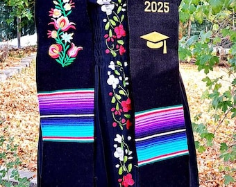 May include: Black graduation stole with colorful stripes and embroidered flowers. The stole has the text "CLASS OF 2025" and a graduation cap.