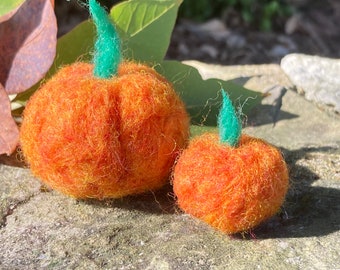 May include: Two needle-felted pumpkins in varying sizes, crafted from textured orange and yellow wool fibers. Each pumpkin features a distinct, upright green felt stem attached to the top center, showcasing a soft, fuzzy, and rounded appearance.