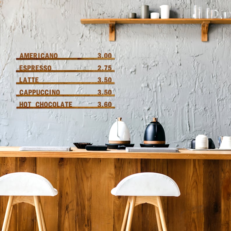 May include: A wooden sign with a coffee menu listing prices for Americano, Espresso, Latte, Cappuccino, and Hot Chocolate. The sign is hanging on a gray wall above a wooden counter with two white bar stools.