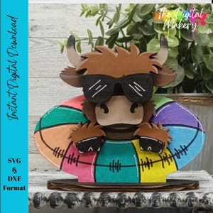 May include: A brown and white Highland cow wearing sunglasses and a colorful inflatable ring. The cow is a wooden cutout and the ring is a layered design with a rainbow of colors.