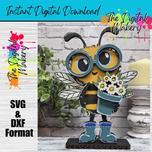 May include: A whimsical, layered wooden bee figure wearing glasses and boots, holding a pot of white flowers. The bee is yellow and black, with blue accents. The image includes the text "Instant Digital Download" and "The Digital Makery."