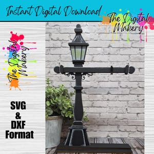 May include: A black street lamp design with a decorative horizontal bar. The lamp has a square base and a detailed top with a glass panel. The text "Instant Digital Download" and "The Digital Makery" are visible. The format is SVG & DXF.
