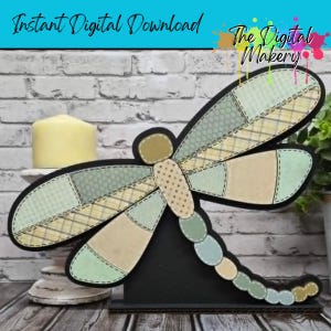 May include: A decorative dragonfly made of fabric patches in various pastel colors, including green, beige, and yellow. The dragonfly has a black outline and is mounted on a black stand. The text "Instant Digital Download" and "The Digital Makery" are visible.