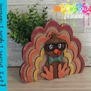 May include: A wooden Thanksgiving turkey decoration with a layered design in shades of brown, orange, and yellow. The turkey wears glasses and a bow tie. The text "The Digital Makery" is at the top. The text "Instant Digital Download" is on the left.