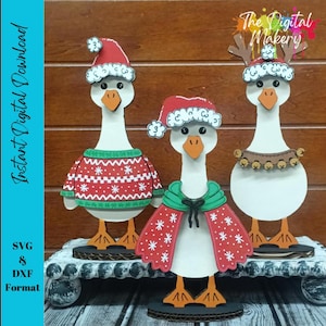 Könnte beinhalten: Drei Holzgansfiguren mit Weihnachtskleidung. Eine Gans trägt einen roten Weihnachtsmannhut und -pullover, eine andere einen roten Umhang und die dritte ein Rentier-Geweih-Stirnband. Der Text "Instant Digital Download" ist sichtbar.