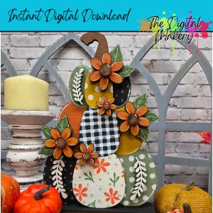 May include: A decorative wooden pumpkin cutout featuring a stacked design with various patterns including black and white buffalo check, yellow polka dots, and floral prints, accented with three-dimensional orange flowers and green leaves.