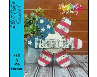 May include: A wooden flower-shaped sign with red, white, and blue stripes and stars. The center of the flower has a white background with the word "FREEDOM" in black letters.