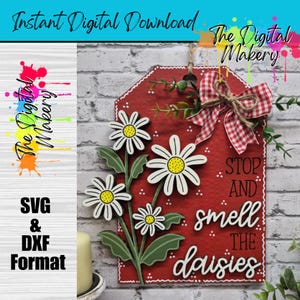 May include: A red wooden sign featuring white daisies and the text "STOP AND smell THE daisies." The sign is decorated with a gingham bow and greenery. The words "Instant Digital Download" and "SVG & DXF Format" are also visible.