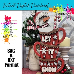 May include: A stack of three red wooden mugs with the words "LET IT SNOW" and snowflake designs. A snowman with a red hat and scarf sits atop the mugs. The image also includes the text "Instant Digital Download" and "The Digital Makery".