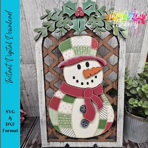 May include: A wooden snowman decoration with a patchwork design, wearing a red scarf and hat, and a carrot nose. The snowman is set in a wooden frame with a holly and berry accent. Text on the left says "Instant Digital Download" and "SVG & DXF Format".