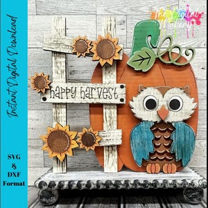 Puede incluir: Decoración otoñal de madera con una calabaza, un búho y girasoles. La calabaza es naranja con un tallo verde. Un búho con alas azules y cuerpo marrón está sentado en la calabaza. El letrero dice "Happy Harvest".