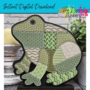 May include: A decorative frog cutout with a patchwork design in various shades of green and beige. The frog has a black outline and is mounted on a black base. Text on the image reads "Instant Digital Download" and "The Digital Makery".
