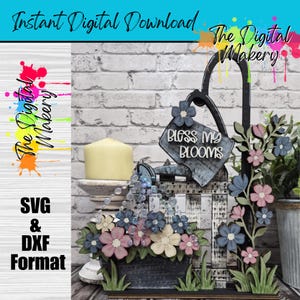 Może przedstawiać: Cyfrowy projekt do pobrania o tematyce ogrodowej z konewką z napisem "Bless My Blooms" i skrzynką na kwiaty. Projekt zawiera różowe, niebieskie i kremowe kwiaty. Widoczne są również słowa "Instant Digital Download", "SVG & DXF Format" i "The Digital Makery".