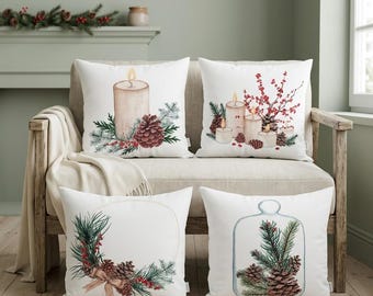 May include: A set of four square white throw pillows featuring watercolor illustrations of holiday themes including lit candles, pine cones, evergreen branches, red berries, a circular wreath with a bow, and a glass cloche containing pine greenery.