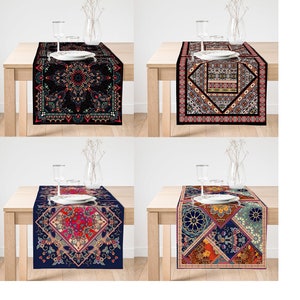 May include: Four patterned table runners are shown on a light wooden table. Each runner has a different design, including floral and geometric patterns in red, blue, and black. The runners are rectangular and appear to be made of fabric. The table is set with glassware.