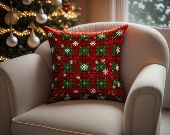 May include: A square decorative pillow with a red plaid pattern, accented with green squares and white snowflakes. The pillow is placed on a cream-colored armchair, with a Christmas tree in the background.