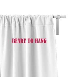 May include: A white curtain hanging on a white rod with the text READY TO HANG printed in pink letters on the fabric. The curtain features a gathered top section and is suspended from a simple white metal rod with a matching mounting bracket.