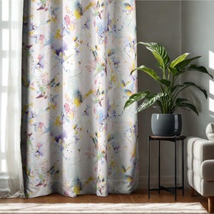 May include: White curtain with a colorful abstract watercolor design. The curtain features splashes of yellow, purple, blue, and pink. The curtain is hanging in front of a window with sheer white curtains.