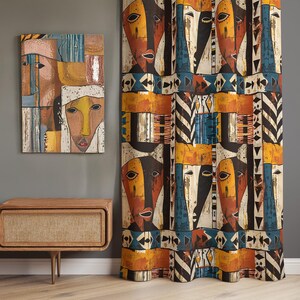 May include: A rectangular wall art piece featuring abstract faces in shades of orange, yellow, blue, and black, displayed next to a floor-length curtain with a repeating pattern of stylized faces and geometric shapes in matching colors.