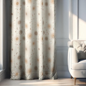 May include: Cream-colored curtain with a repeating pattern of suns, moons, and stars in a warm, golden hue. The curtain hangs in front of a window, with a glimpse of a white sofa and decorative wall art in the background.