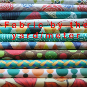a stack of colorful fabrics with the words fabric by the yard