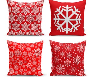 May include: Four red throw pillows with white snowflake patterns. Two pillows feature a large snowflake design, while the other two have a smaller snowflake pattern.