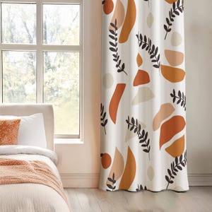 May include: A white curtain panel featuring a repeating pattern of abstract shapes in shades of burnt orange, terracotta, and beige, interspersed with dark brown botanical leaf sprigs. The fabric hangs vertically with soft folds.