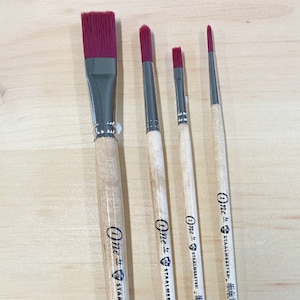 May include: Four paint brushes with red bristles and wooden handles. The handles are labeled "One +" and "Stahlmeister" with a diamond logo.
