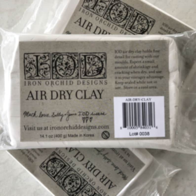 May include: Two packages of Iron Orchid Designs air dry clay. The packages are white with brown text and a logo. The text on the package reads "Iron Orchid Designs Air Dry Clay" and "14.1 oz (400 g) Made in Korea".