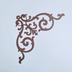 May include: A brown, intricate, decorative corner piece with a scroll design. The piece is made of wood and has a delicate, ornate pattern.