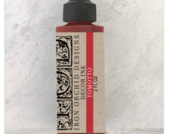 May include: A 2-ounce bottle of Iron Orchid Designs Decor Ink in the color Tomotto. The bottle has a black cap and a label with a red stripe and the brand name and color name.